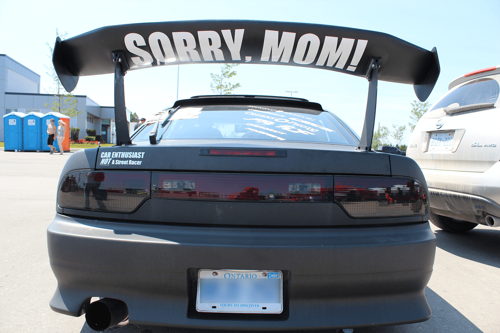 A photograph of a street race car with a spoiler that has the words "Sorry Mom!" printed on it. Removing after-market upgrades is one way to get more money for your car.