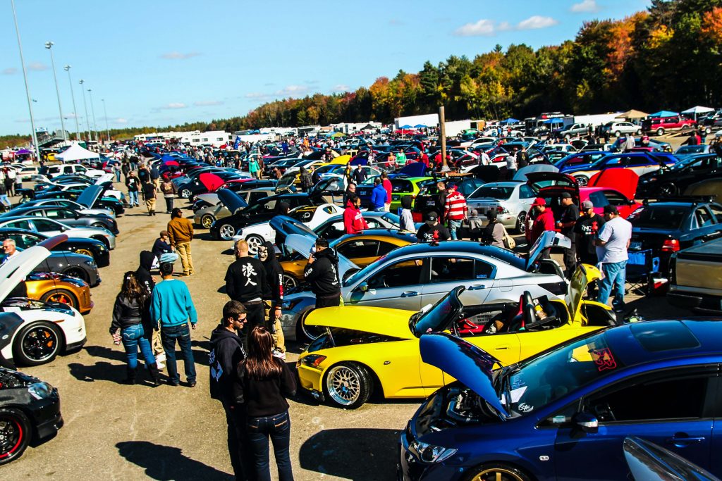 people viewing cars in a parking lot at a car show