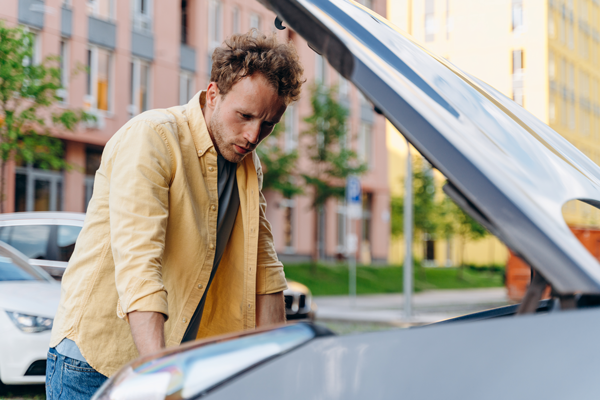 man evaluating car condition looking under hood of car