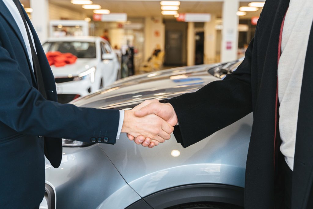 two men in a car dealership shaking hands after a negotiation