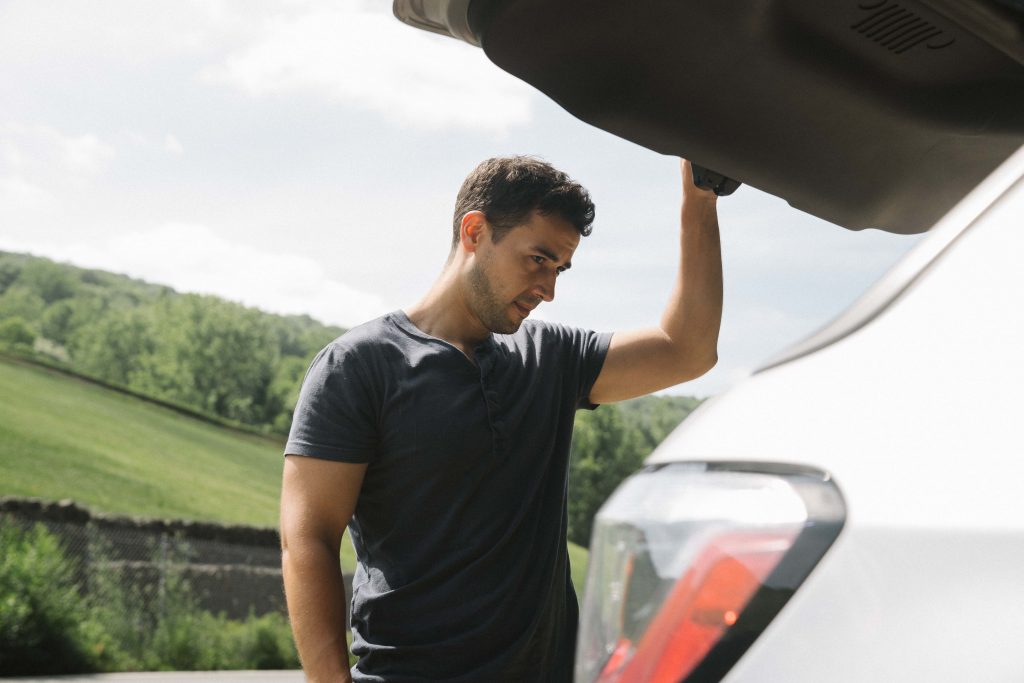 guy opening the trunkk of his car and looking inside