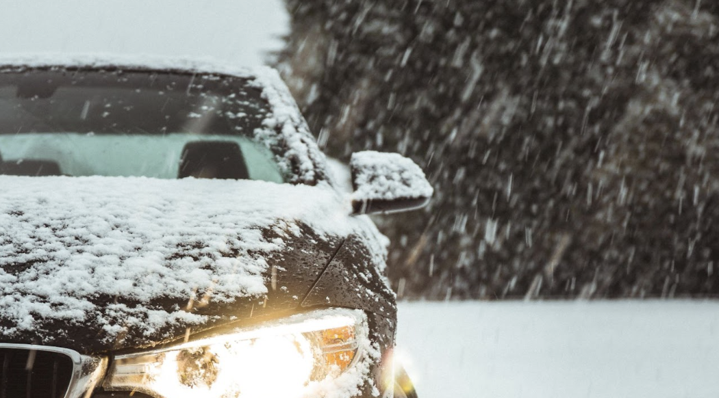 vehicle parked in the snow with headlights on