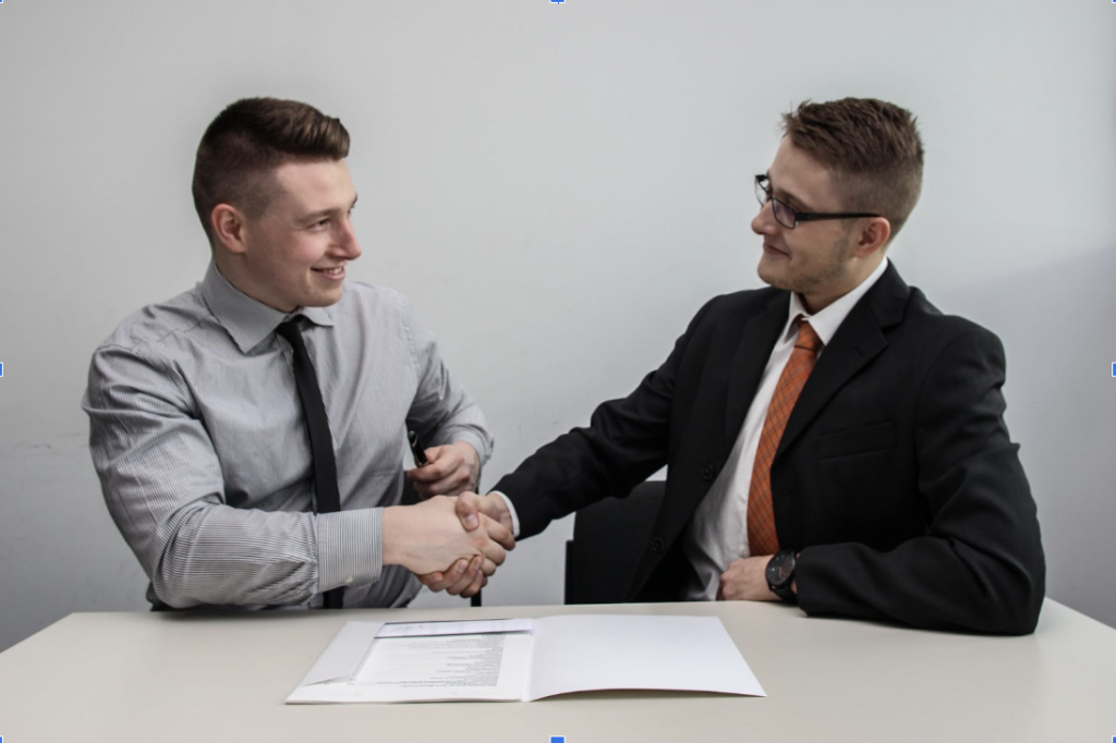 two men shaking hands on a car loan payment deal